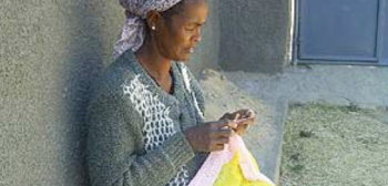 Beneficiarios del convenio, como esta artesana etíope que está bordando su producto.